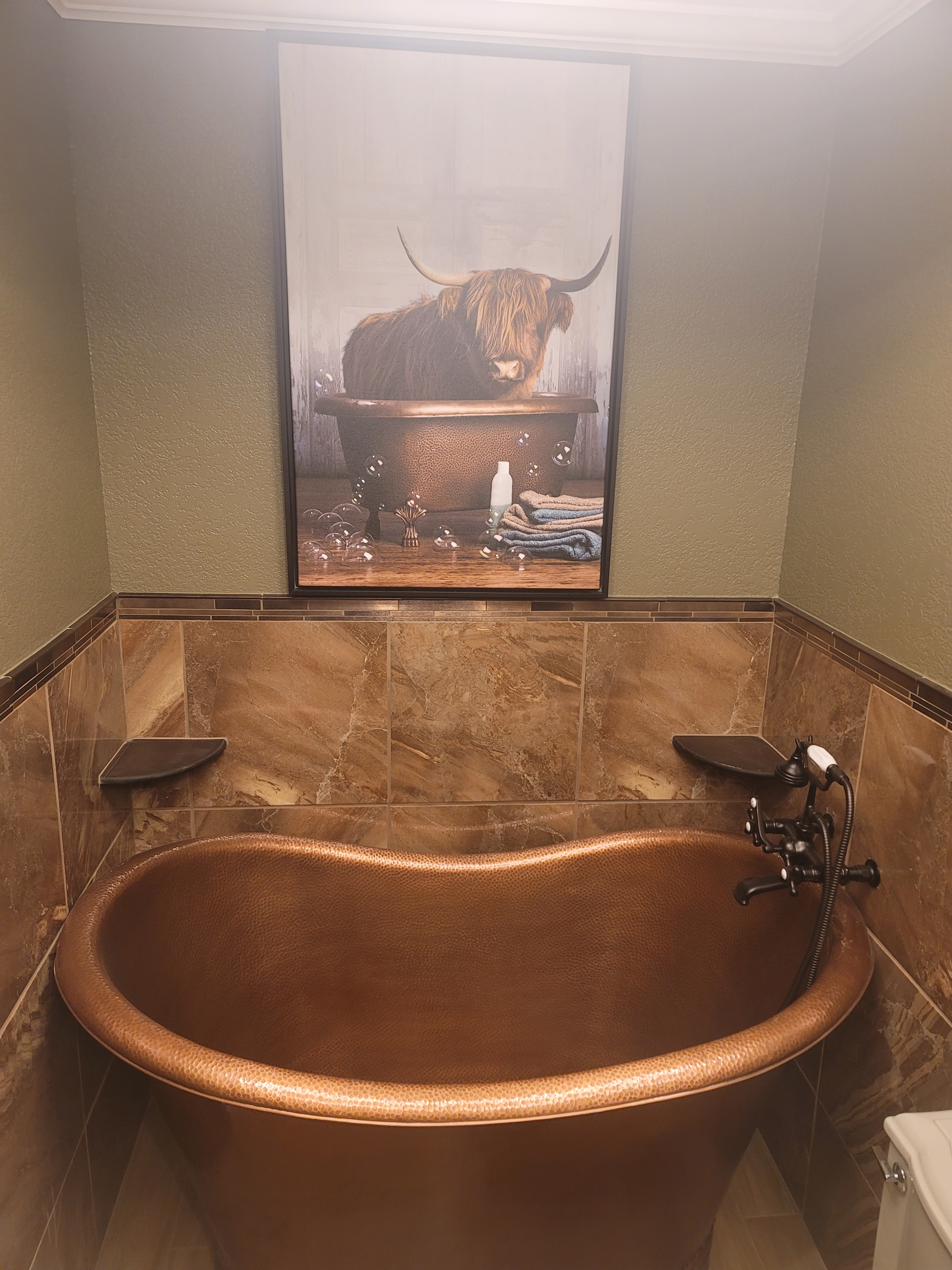 Hammered copper freestanding bathtub with wall-mounted filler in a finished bathroom